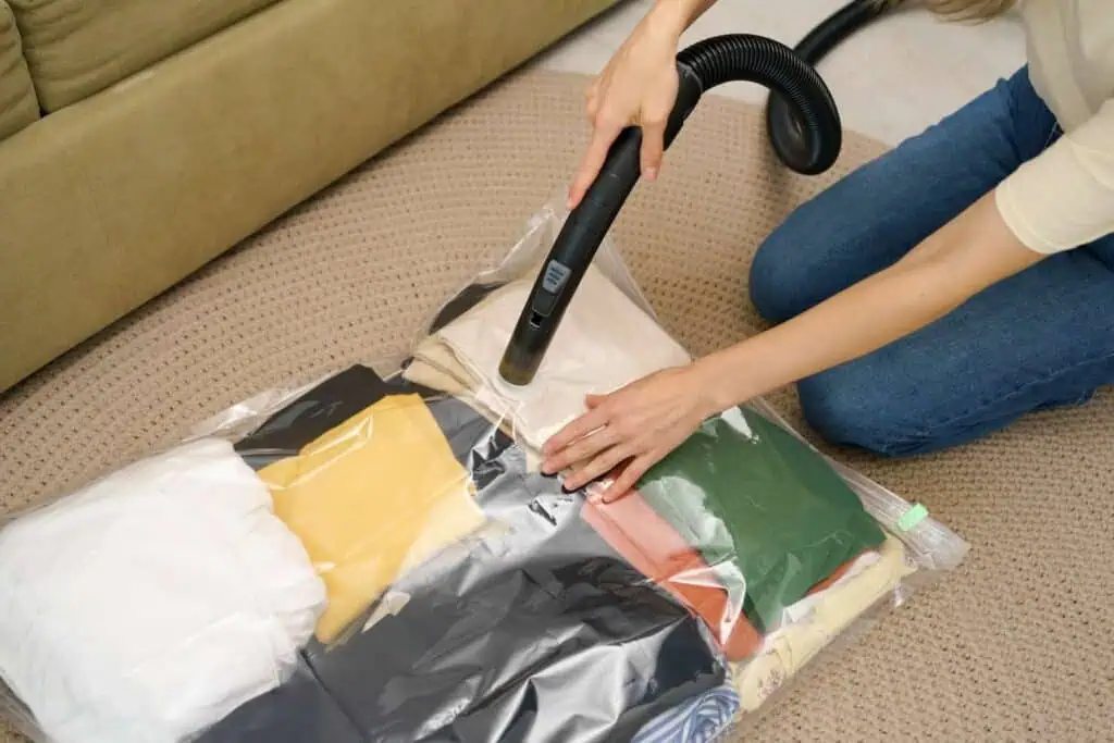 a personal attaches a hose to a vacuum seal bag full of clothing