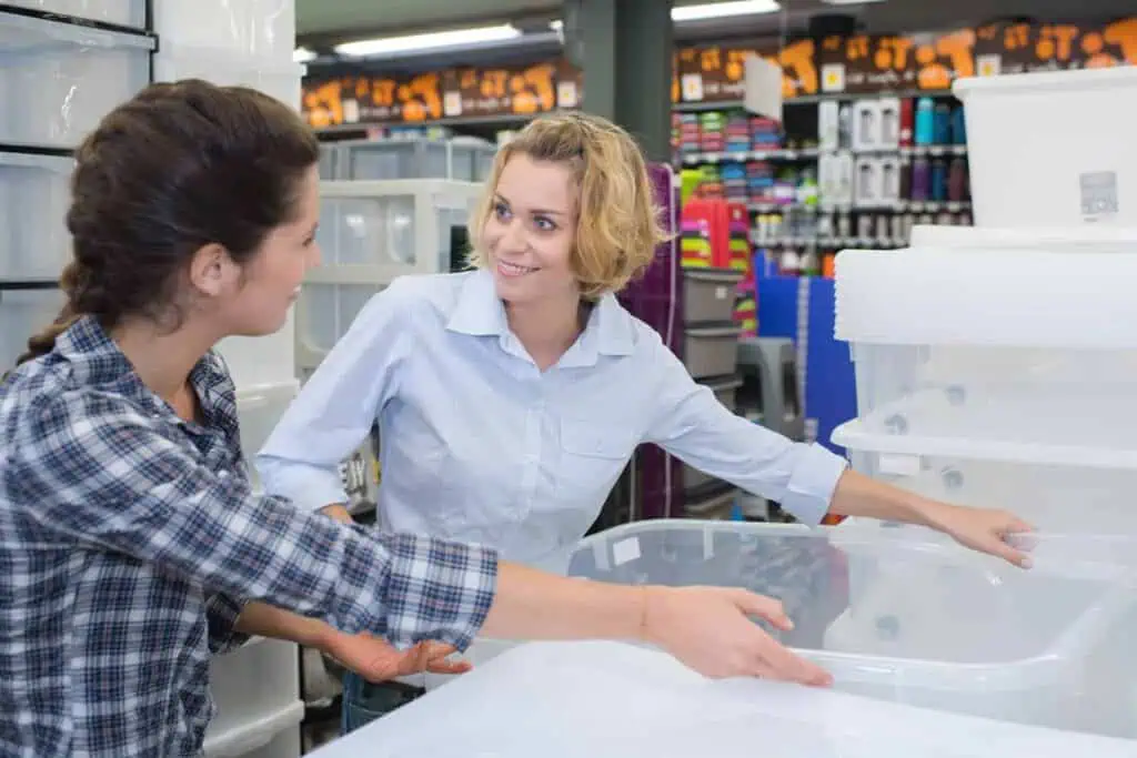 Two women look at plastic storage tubs in a store