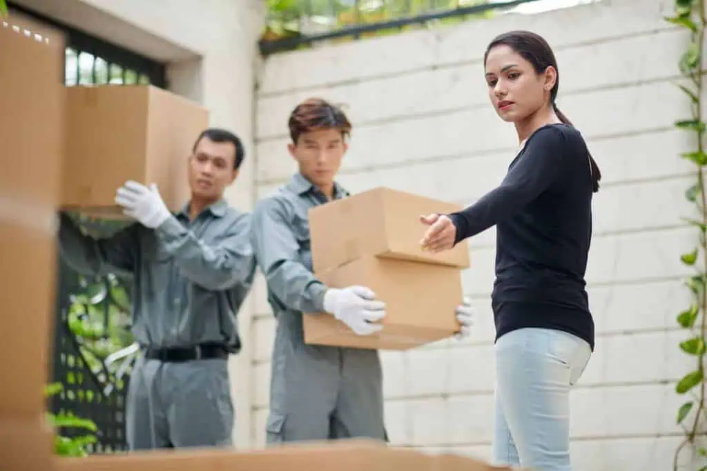 A woman directs movers where to put some boxes