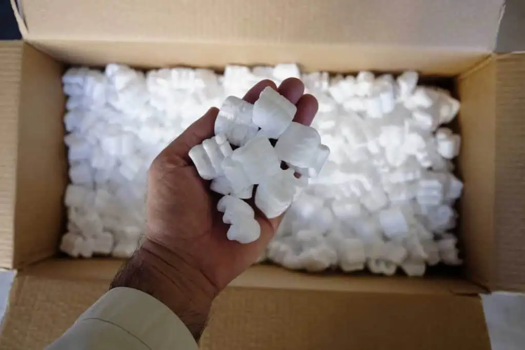 an aerial shot of someone's hand dumping packing peanuts into a box
