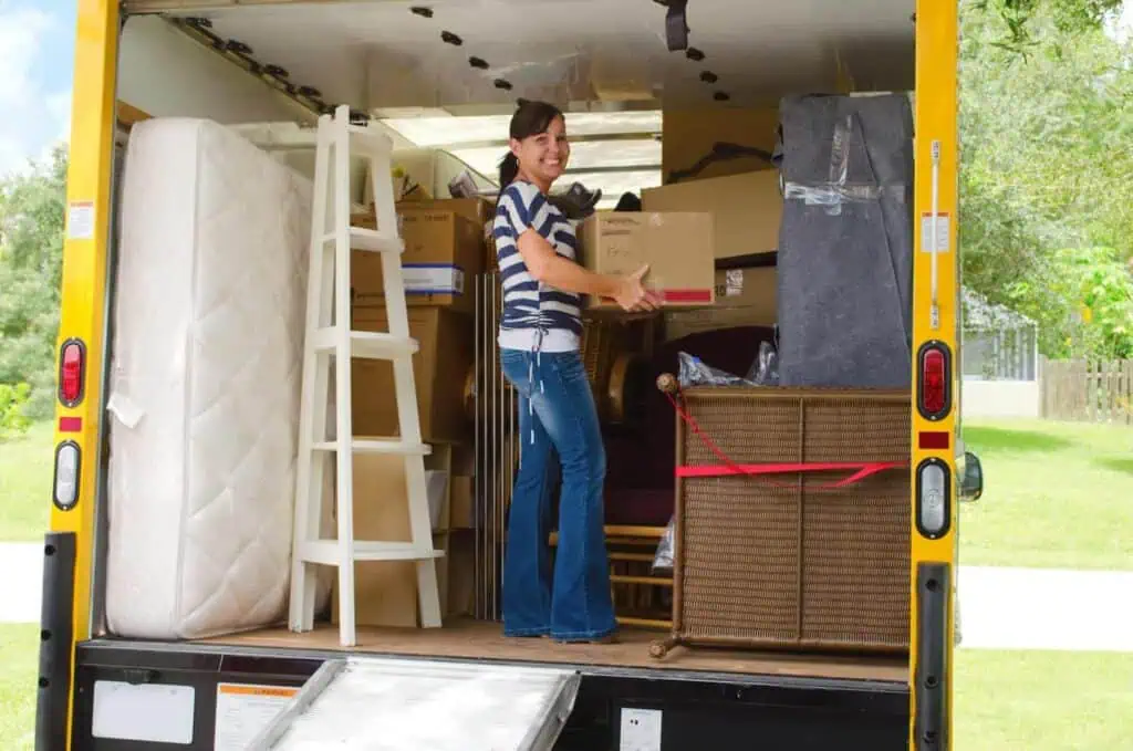 A woman happily loads a yellow moving truck