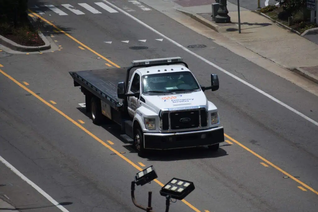A white AAA tow truck drives down a road