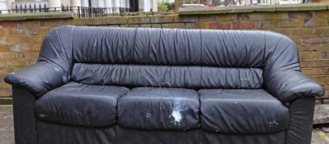 an old black couch is sitting at the curb