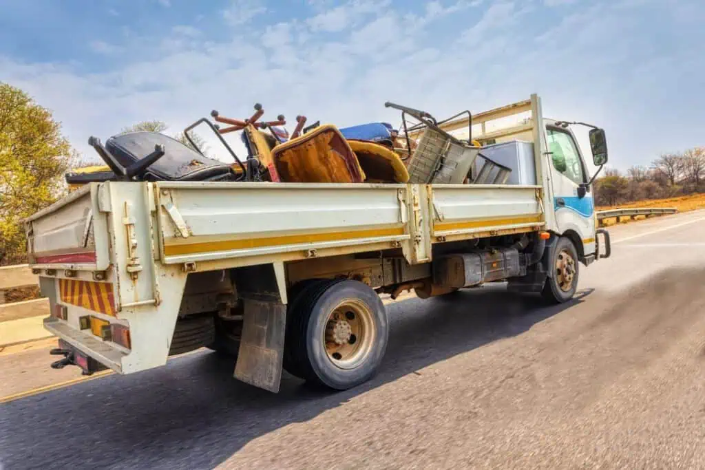 A large truck carries trashed or recycled furniture in its bed