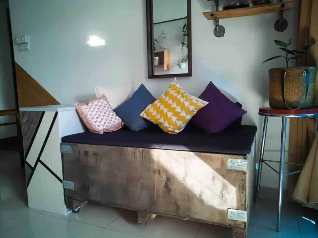 a couch has been upcycled into a smaller seat with cushions using a wooden crate