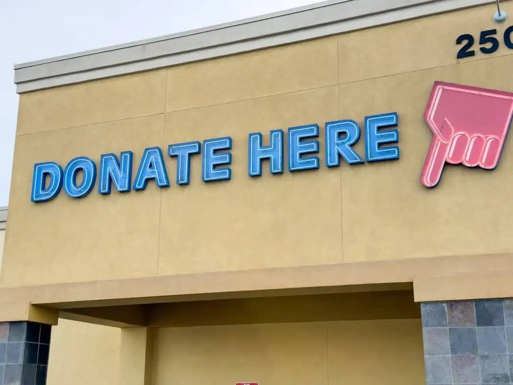 an image of a large sign for a Goodwill office that reads "donate here" along with a stylized hand pointing to the side