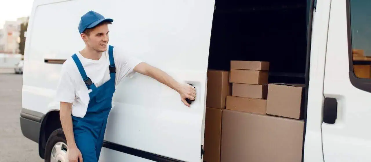 A mover closes the door to a moving truck with boxes inside