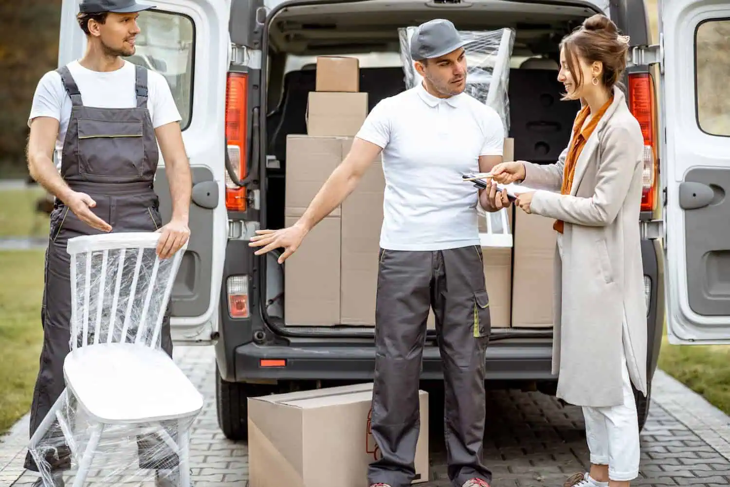 A woman chats with two movers who are unloading a packed truck