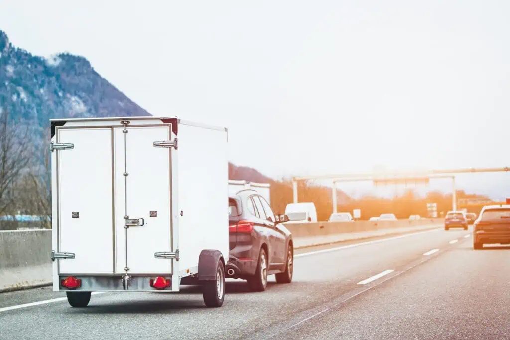A car tows a covered trailer down the highway
