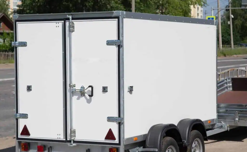 two different types of moving trailers (cargo and open) are parked in a lot