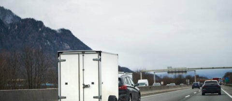 A car tows a cargo trailer down a highway