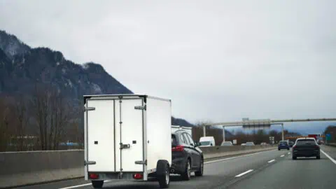 A car tows a cargo trailer down a highway