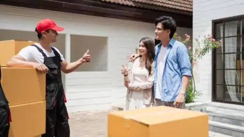 A couple is happy that a mover is here to load their items, and the mover is giving them an enthusiastic thumbs-up.