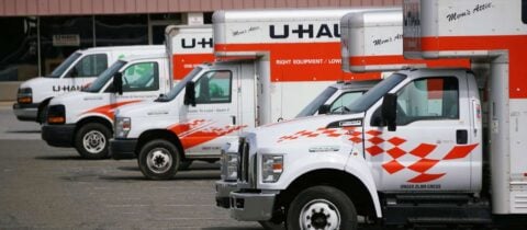 Uhaul trucks of different sizes are parked in a row in a lot