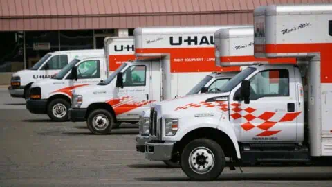 Uhaul trucks of different sizes are parked in a row in a lot