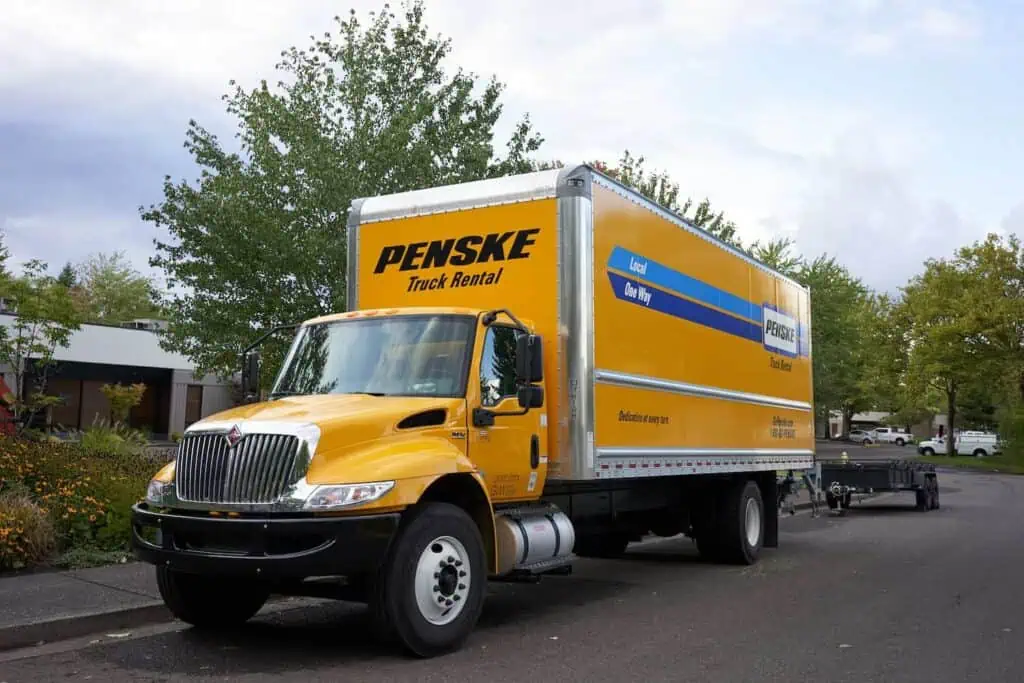 A Penske truck is parked at the side of a residential street
