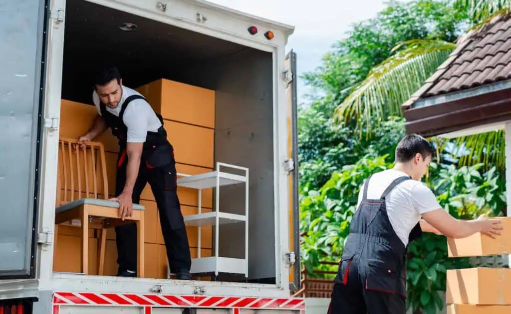 Two movers in dark blue overalls load a truck