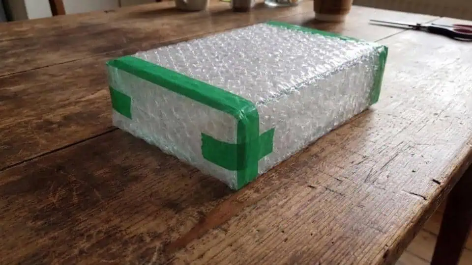 An illustration of packing tape being securely applied around a  bubble wrapped object.