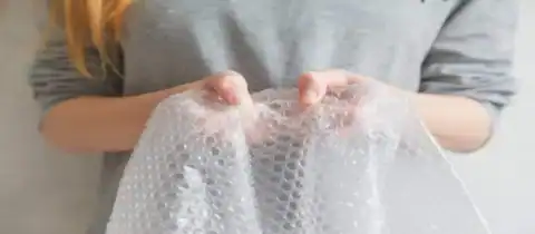 Close-up of a person holding a sheet of bubble wrap with both hands.