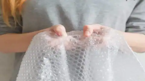 Close-up of a person holding a sheet of bubble wrap with both hands.