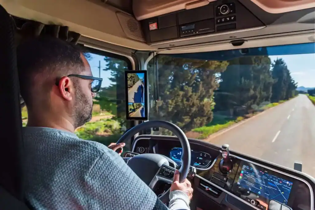Man driving a rental truck on a clear road.
