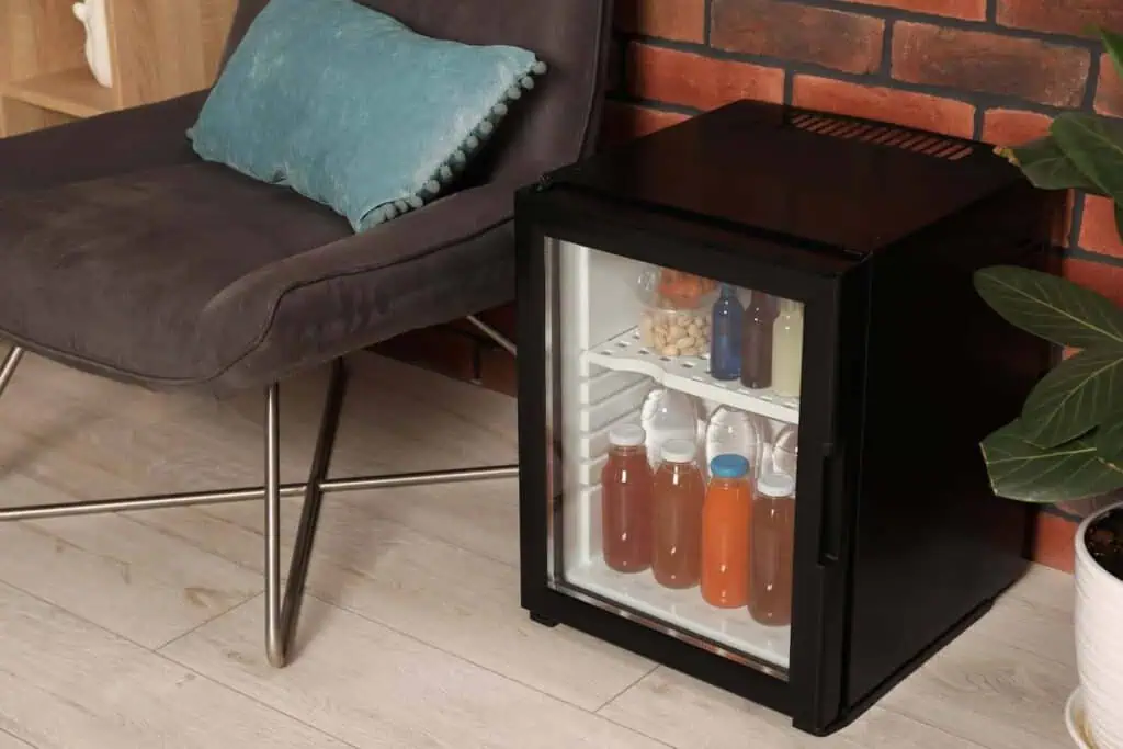 A mini fridge filled with snacks and drinks sits in a living room