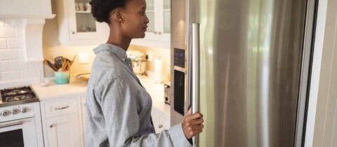 a woman looks into the fridge in her kitchen