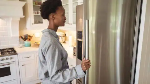 a woman looks into the fridge in her kitchen