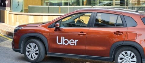 A copper colored compact suv with UBER written on the side drives down the road