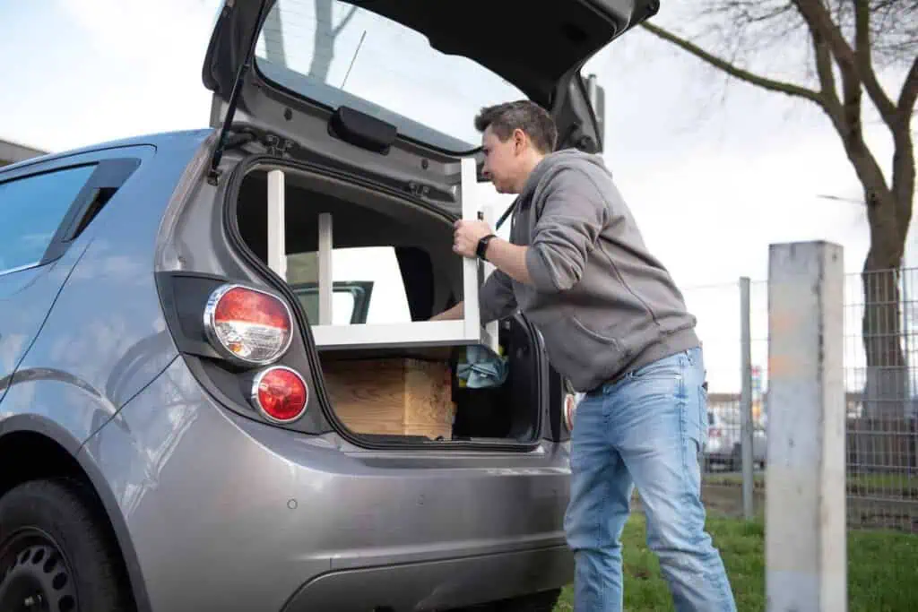 A person loads furniture into a packed car