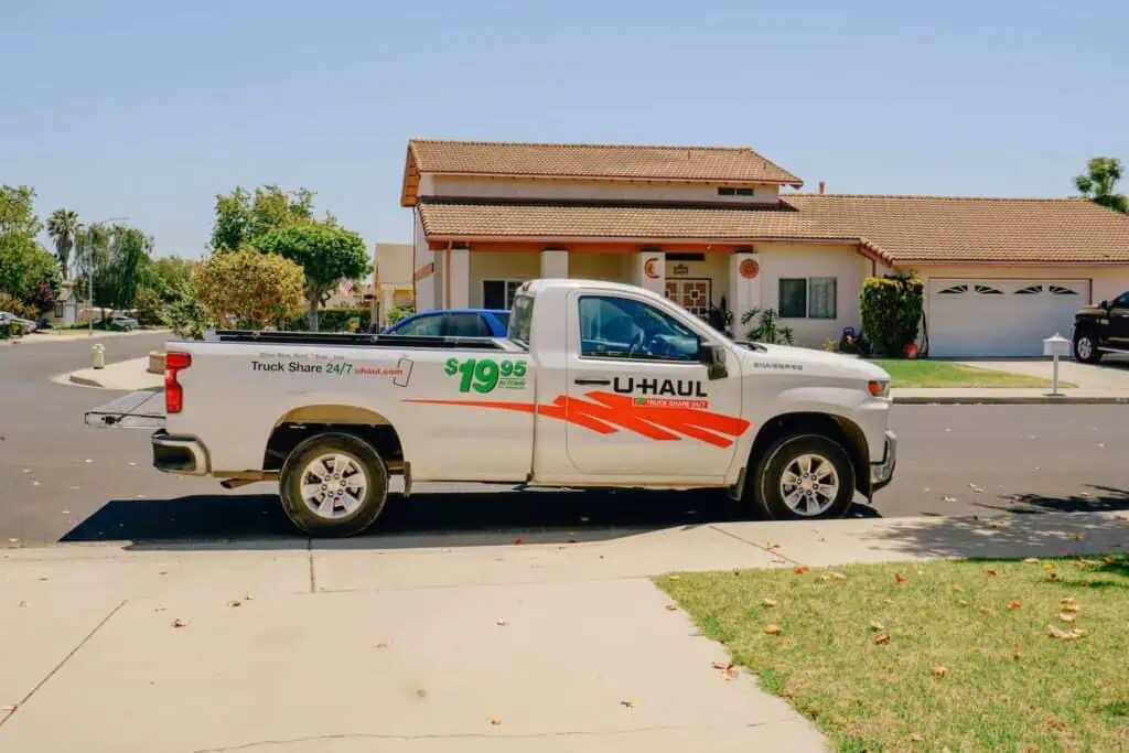 A Uhaul pickup truck for rent is parked at the curb in front of a home