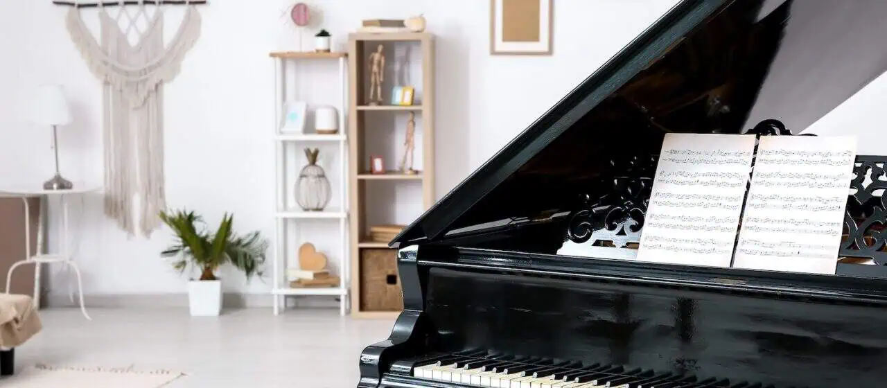 A piano sits in a living room. The photo is shot in such a way that the piano takes up only half of the frame, showing the rest of the room in the other half.