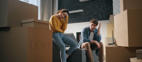 A couple sitting at home among moving boxes