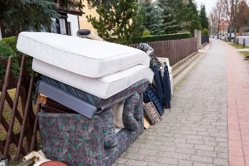 Rubbish left on the road, including mattresses and old furniture.