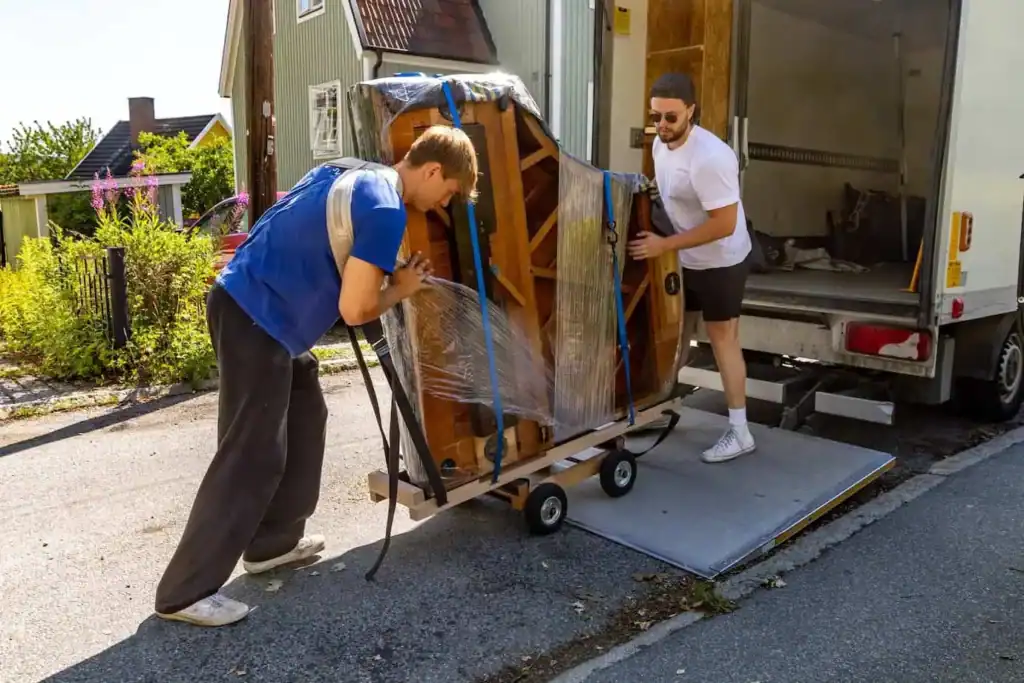 Two men loading a piano onto a moving truck