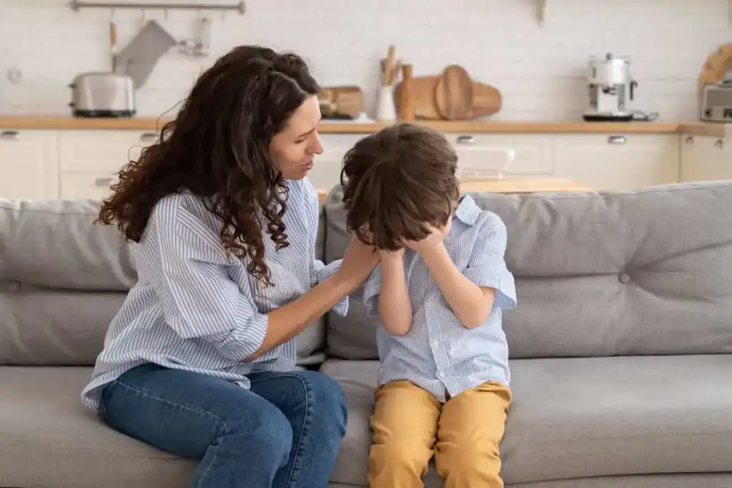 Mother comforting child about moving stress while sitting on couch in new home