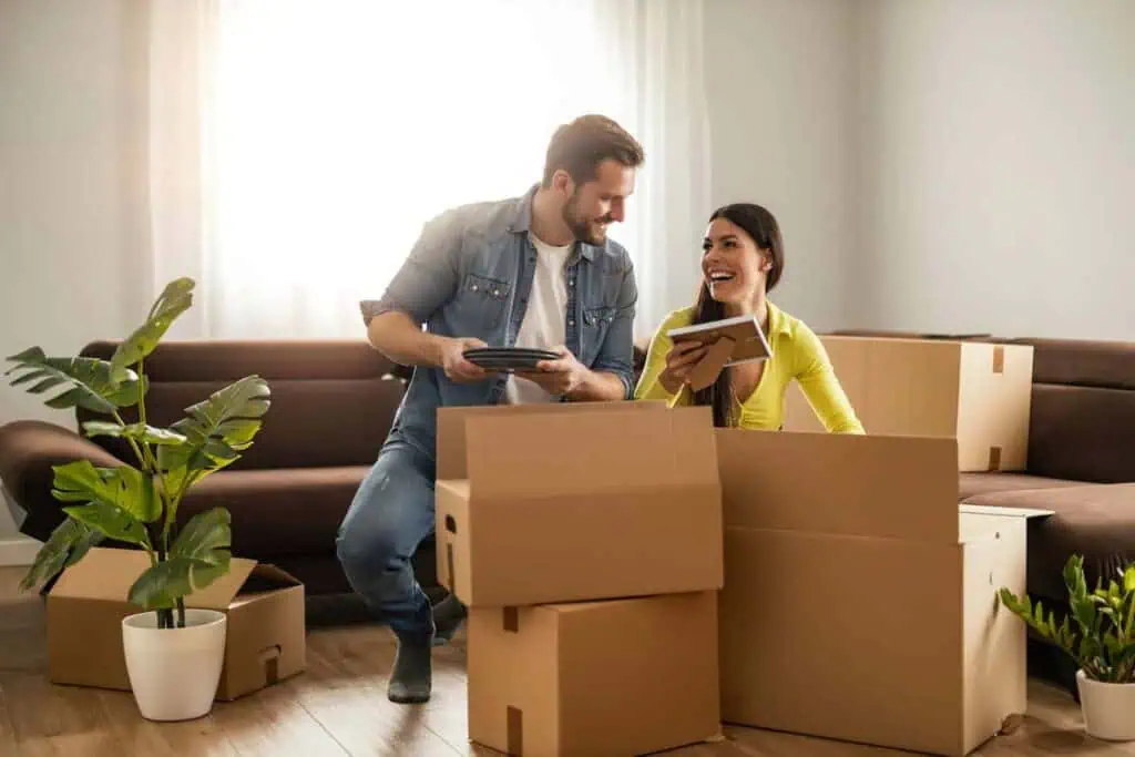 a man and woman happily pack boxes in their apartment