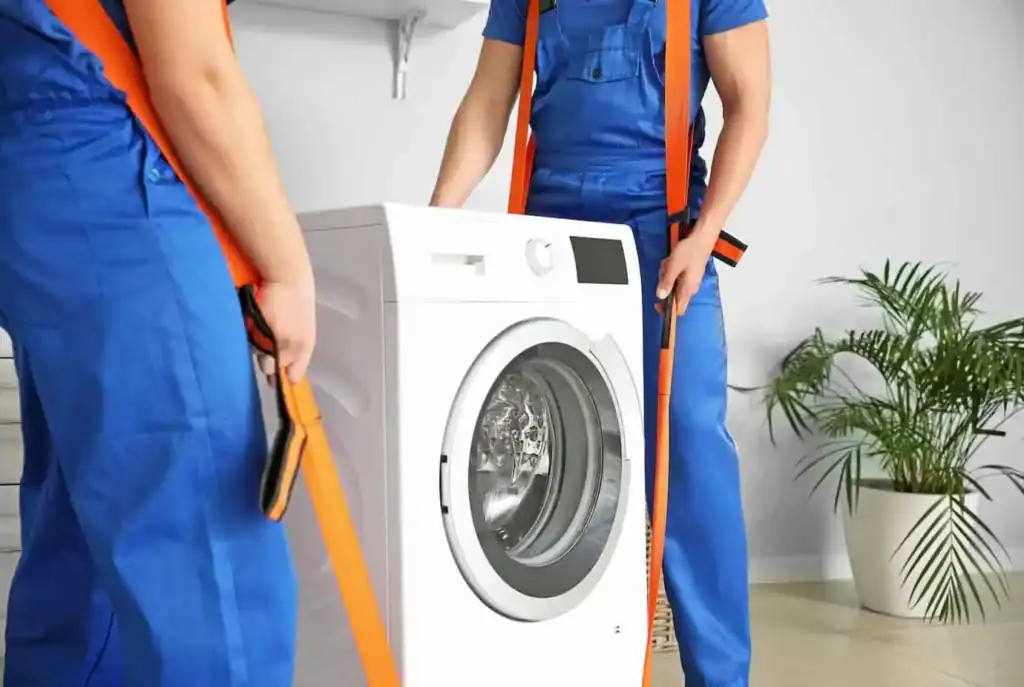 Movers using lifting straps to carry a washing machine during a move