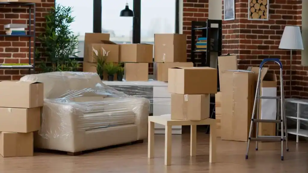 Living room filled with packed moving boxes and wrapped furniture