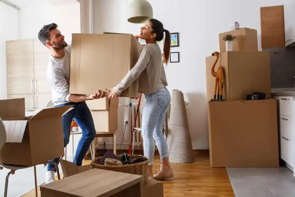 Couple lifting heavy moving box inside their new home