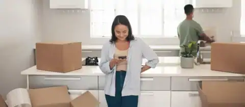 Smiling woman using her phone to explore moving apps for a relocation