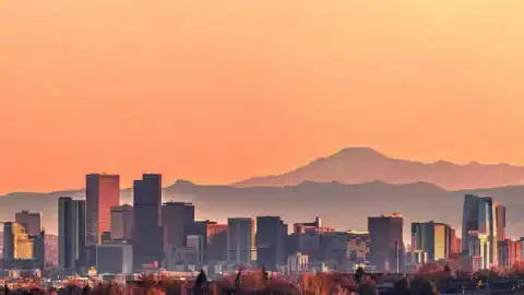 Denver CO cityscape with mountain backdrop during sunset