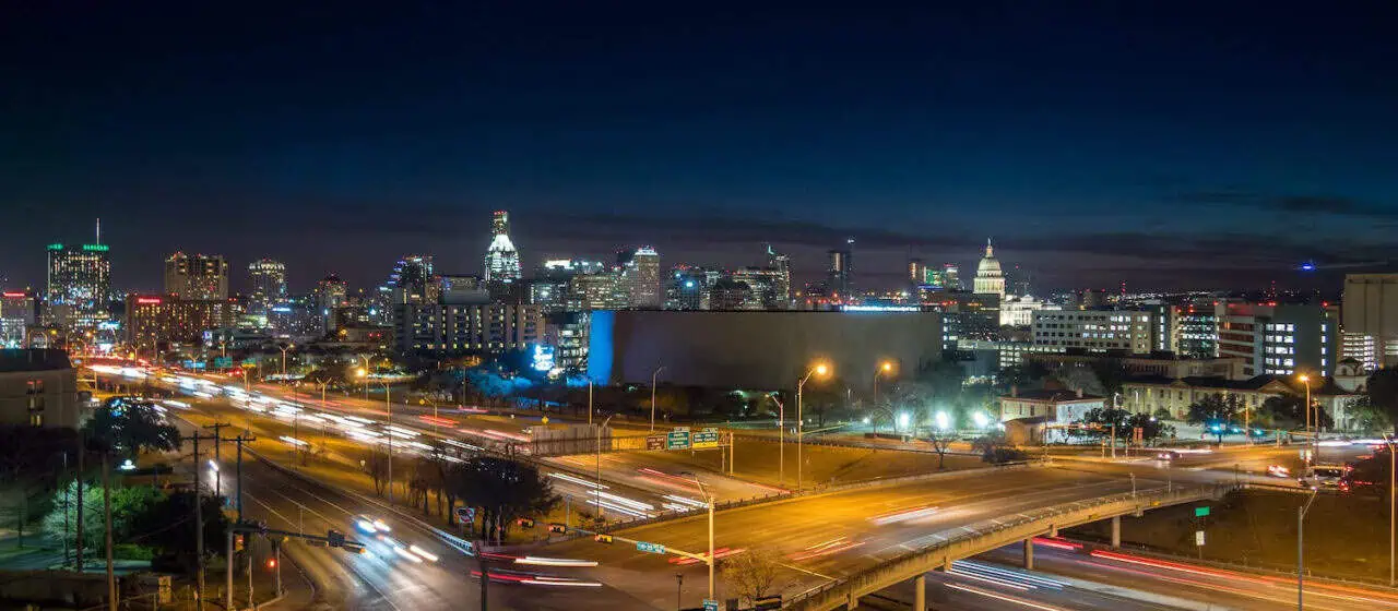 a view of traffic going by along highways at night near Austin, TX's downtown