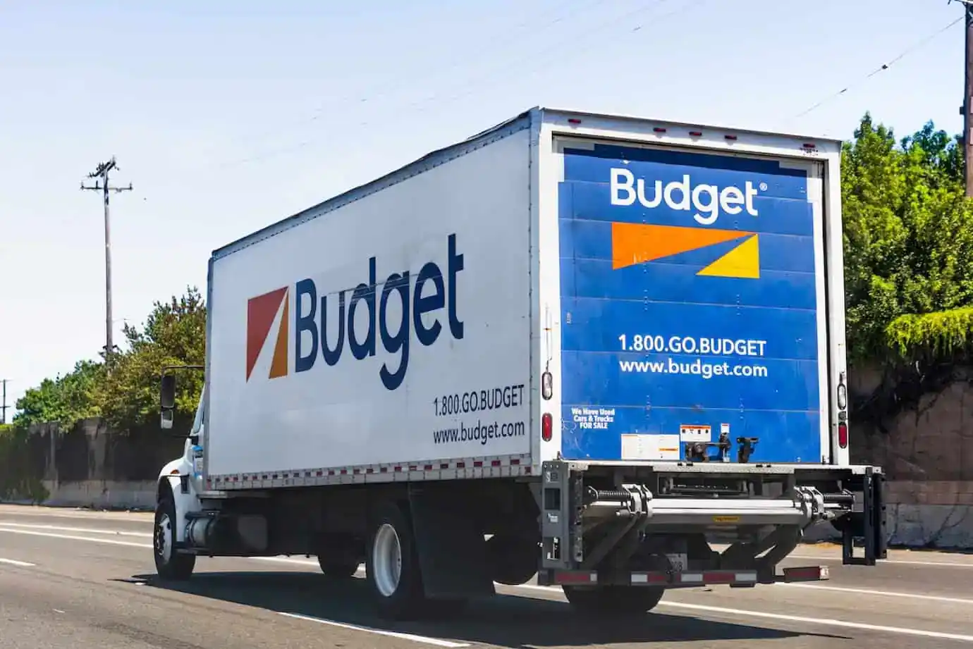 White Budget moving truck with blue and orange logo driving on road