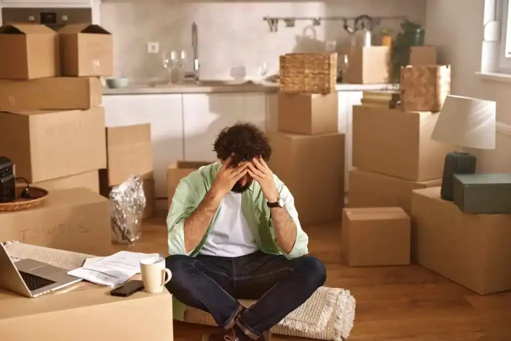 Stressed man surrounded by moving boxes