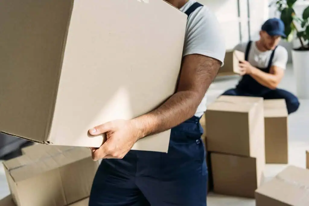 two movers carry and prepare boxes for a move
