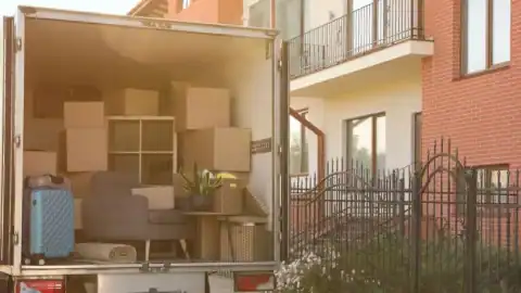 Open moving truck packed with boxes and furniture outside a house