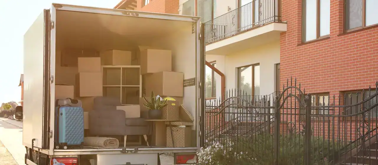 Open moving truck packed with boxes and furniture outside a house