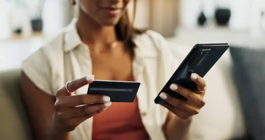 Person holding a credit card and phone, paying movers for relocation services