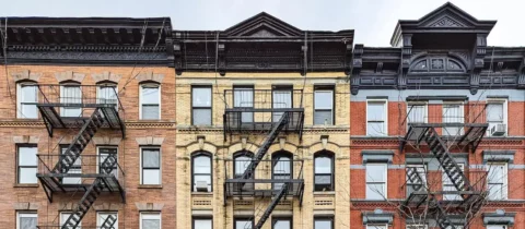 Historic apartment buildings with ornate facades and exterior fire escapes in a city neighborhood